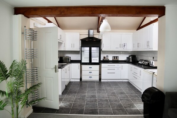 A kitchen with white cabinets, a black refrigerator, and a tiled floor. - City Centre Guest House - Gloucester Park (Gloucester)