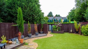 A well-maintained backyard with a wooden deck, a variety of potted plants, and a neatly trimmed lawn. - City Centre Guest House - Gloucester Park (Gloucester)