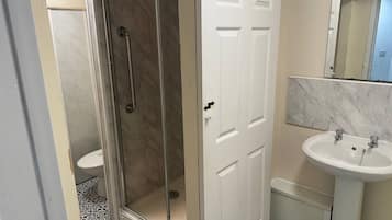 A bathroom with a glass-enclosed shower, a white sink, and a toilet.