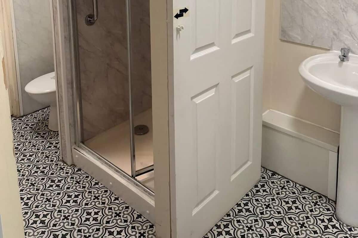 A bathroom with a shower enclosure, a toilet, a sink, and a mirror.