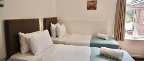 Una habitación de hotel con dos camas, una ventana con cortinas y una obra de arte colgada en la pared.