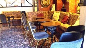A cozy lounge area with patterned sofas, a round table, and a blue chair. - The Derby Hotel (Blackpool)