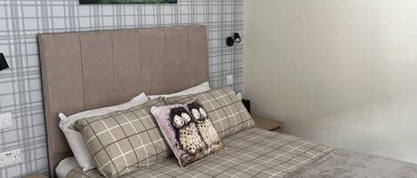 A neatly arranged bedroom with a bed, pillows, a nightstand, and a wall with two paintings.