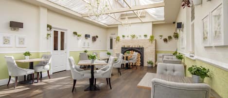 A spacious room with a high ceiling, a fireplace, and several seating areas.
