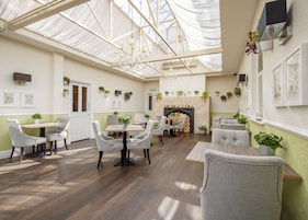 A spacious room with a high ceiling, a fireplace, and several seating areas.