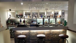 A bar area with stools, a counter with bottles, and hanging glasses. - The Highworth Hotel (Swindon)