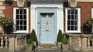 A traditional building with a light blue door, a sign above reading "The Highworth Restaurant, Bar, Hotel", and two windows on either side of the door. - The Highworth Hotel (Swindon)