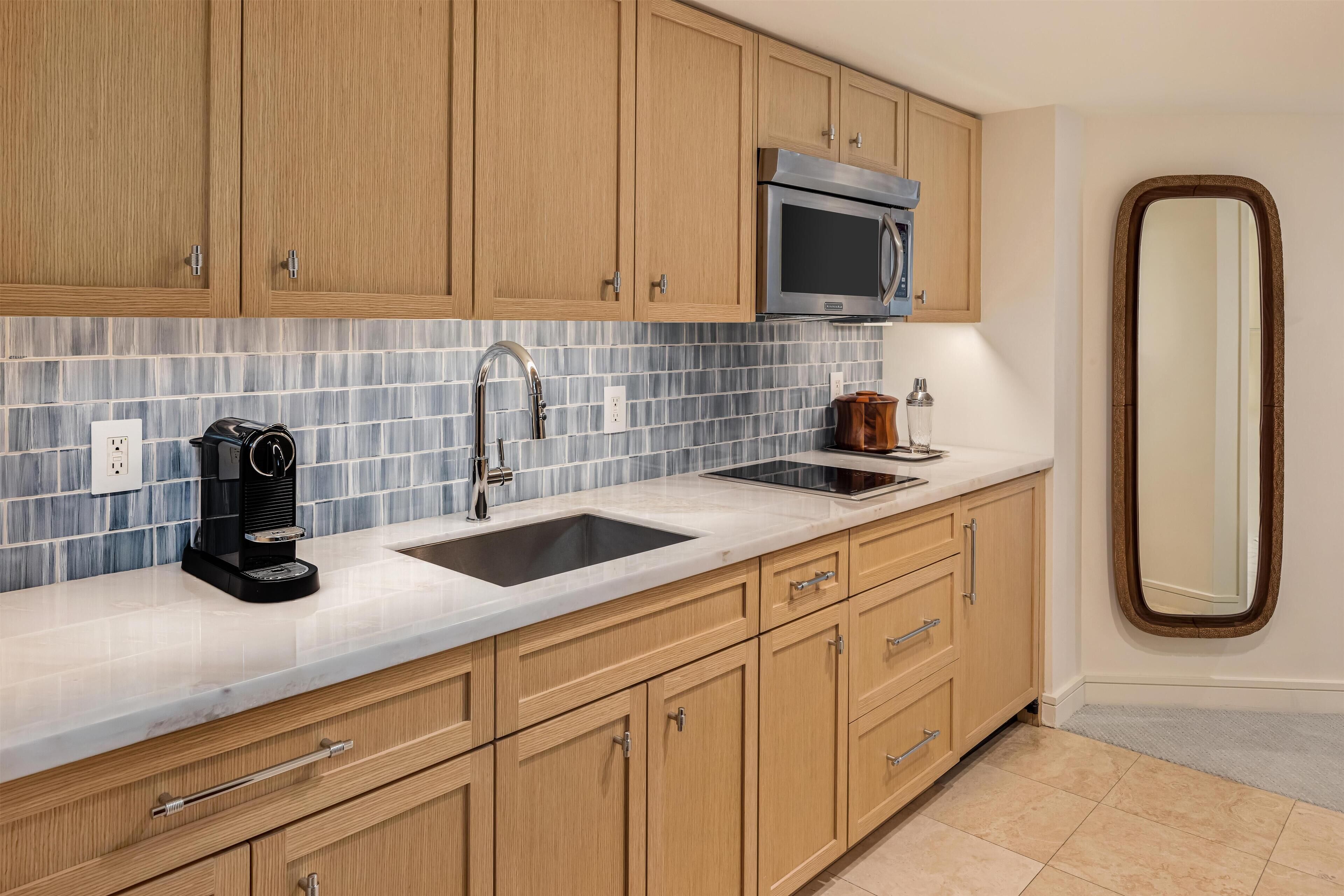 Una cocina moderna con armarios de madera, un microondas de acero inoxidable, una cafetera y un lavamanos doble.
