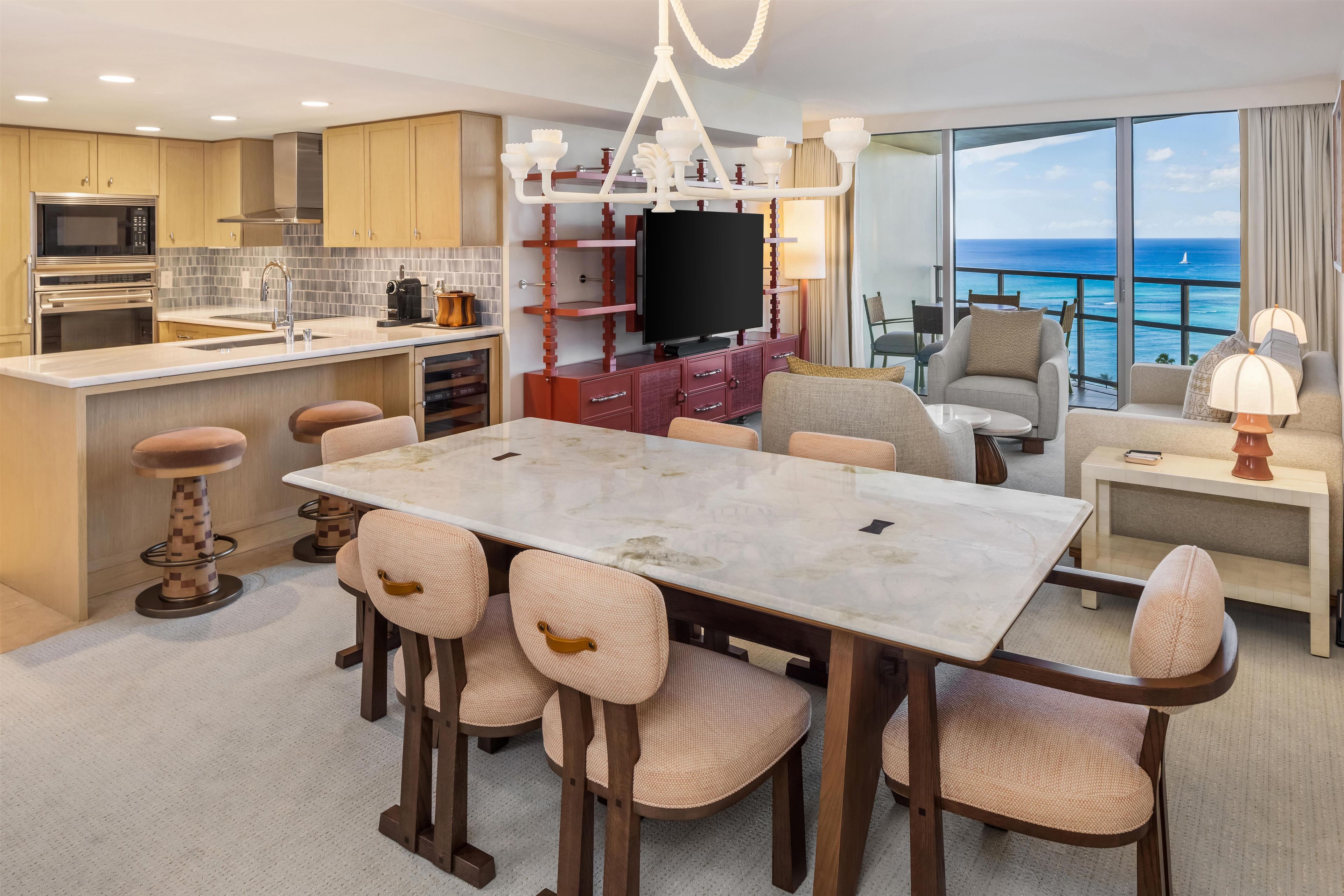 Una cocina moderna con electrodomésticos integrados, un comedor con mesa de mármol y una sala de estar con vista al océano.