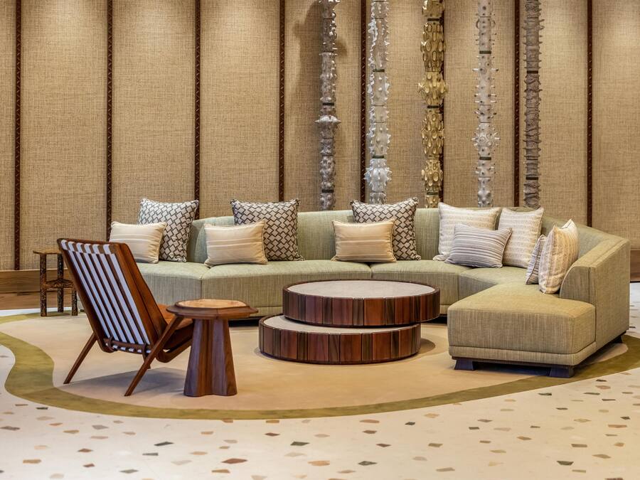 Un salon moderne avec un canapé d’angle, une table basse ronde, une chaise en bois et un tapis à motifs.