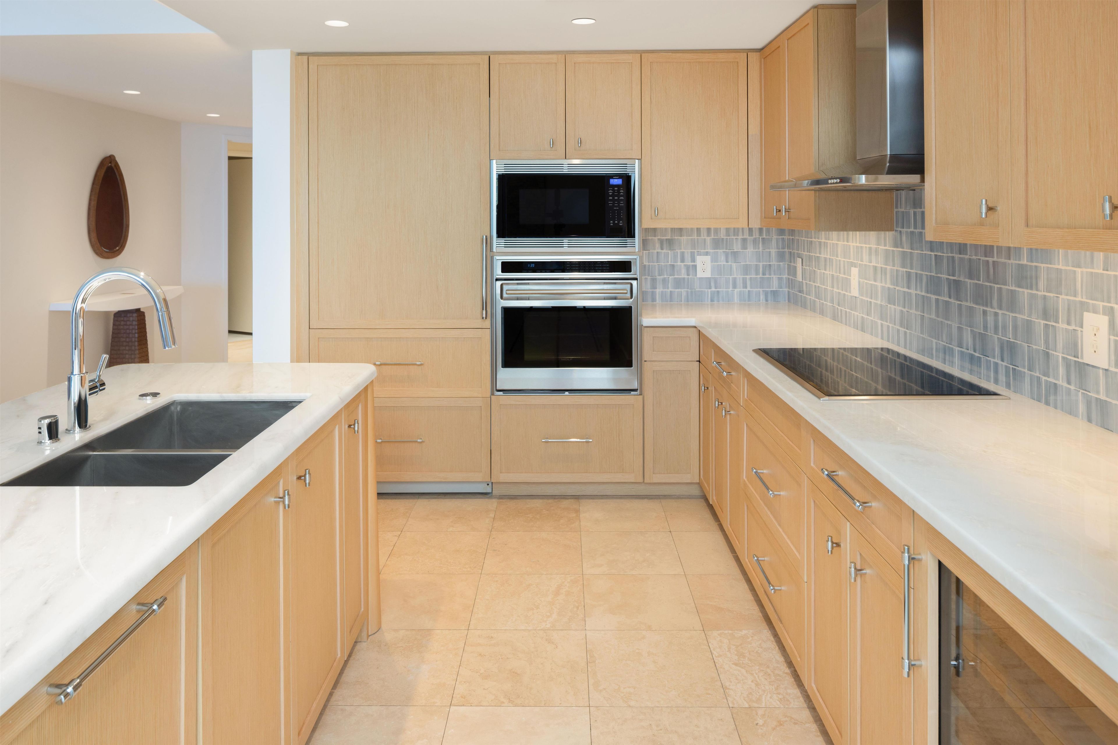 A modern kitchen with wooden cabinets, stainless steel appliances, and a tiled backsplash.