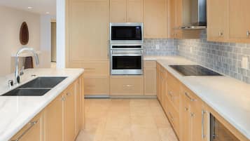 A modern kitchen with wooden cabinets, stainless steel appliances, and a tiled backsplash.