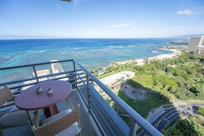 A balcony with a table and chairs overlooking a beach and ocean. - Ka Laʻi Waikiki Beach, LXR Hotels & Resorts (Honolulu)