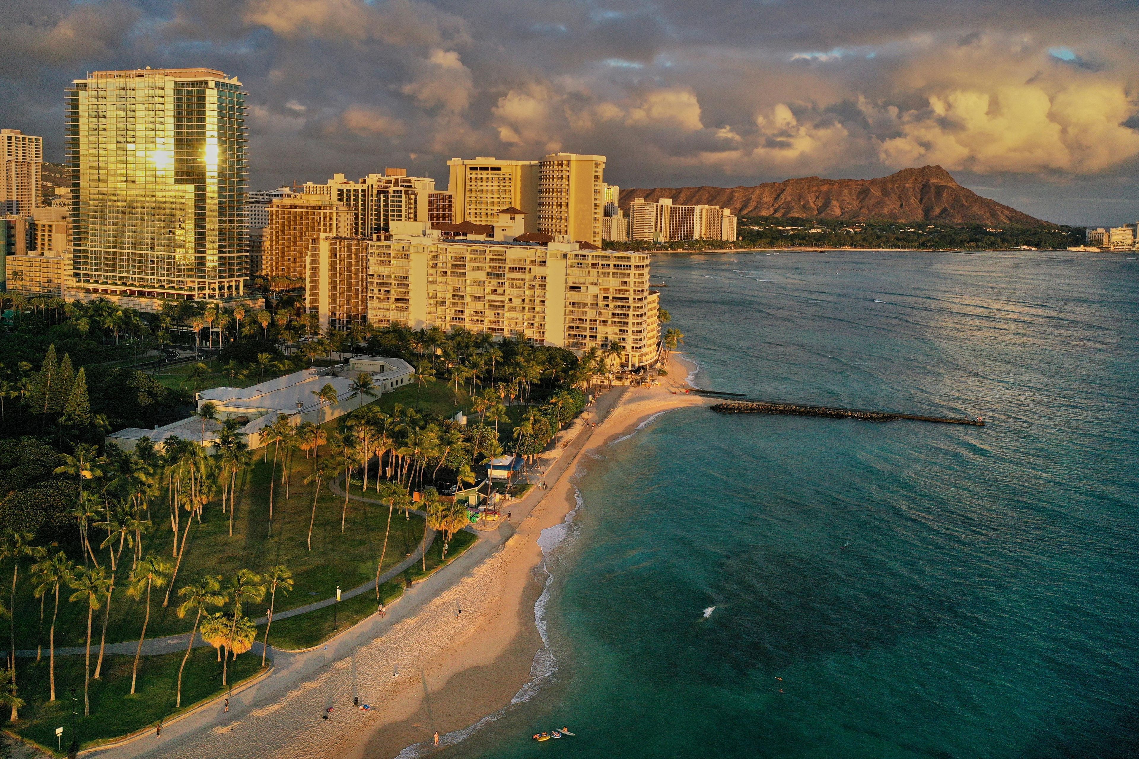 A coastal cityscape with high-rise buildings, a beach, and a mountain in the background.