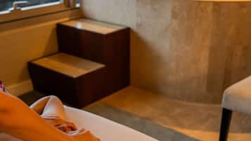 Relax in a spacious bathroom with a large bathtub and a window overlooking lush surroundings.