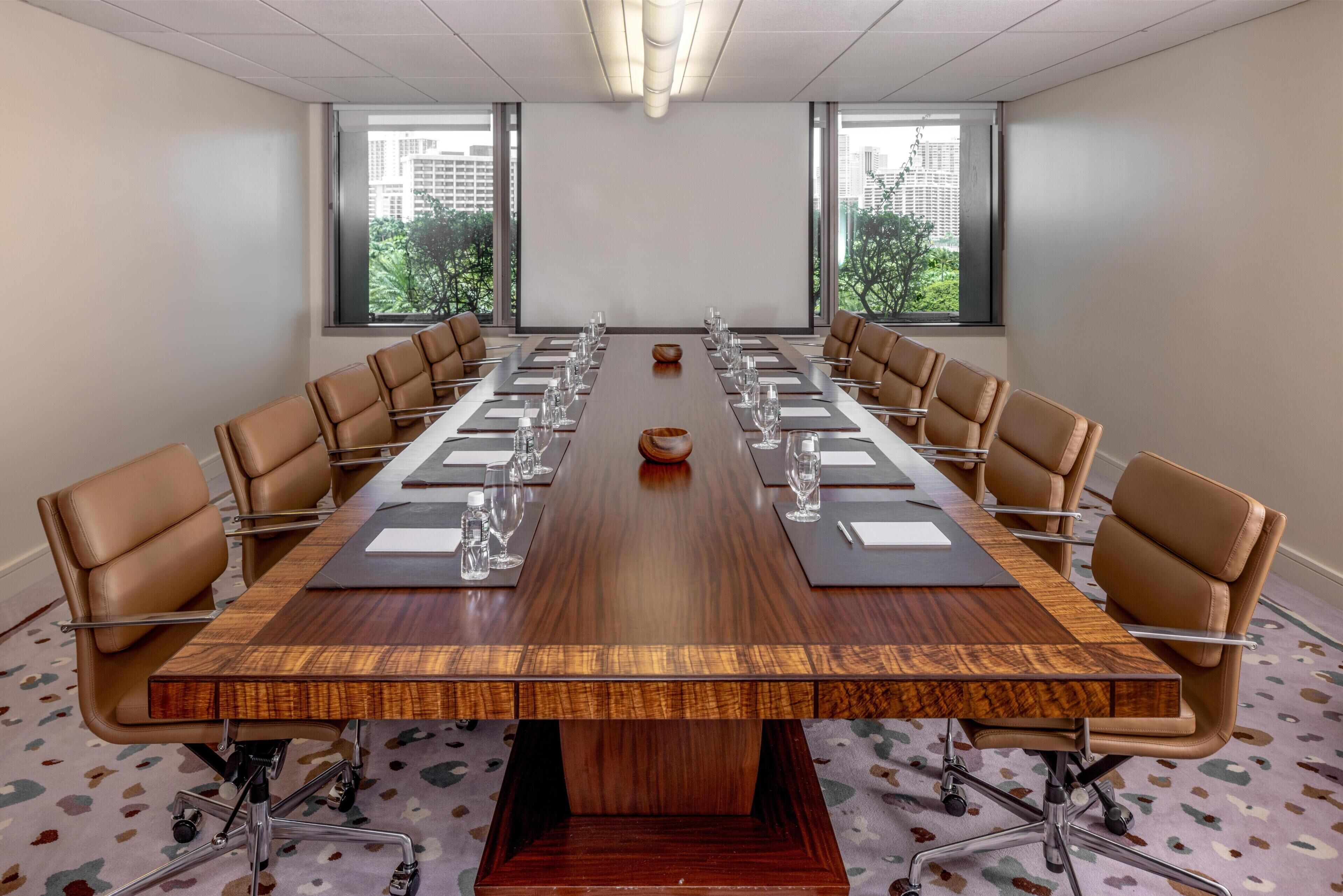 Une salle de conférence dotée d’une longue table, de fauteuils en cuir et de grandes fenêtres offrant une vue sur la ville.