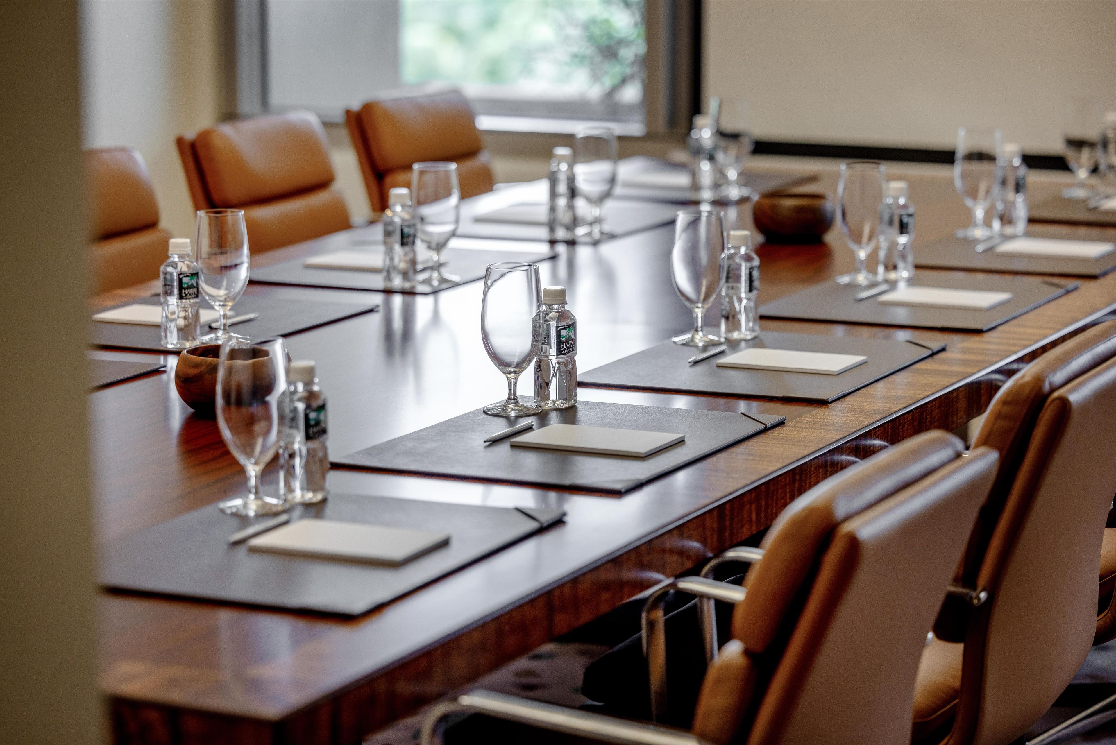A conference room with a long table, multiple chairs, water bottles, and glasses.