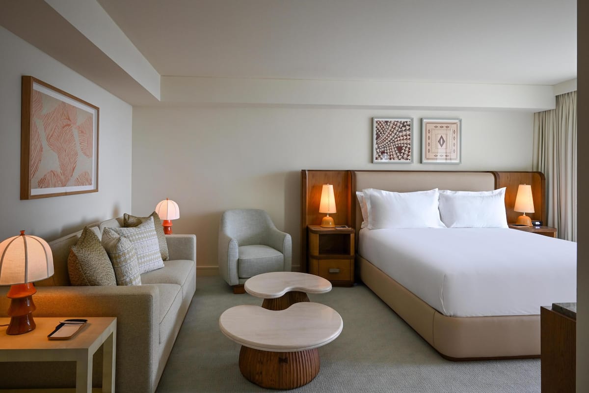 Een hotelkamer met een bed, een bank, een stoel, een klein tafeltje en twee bedlampen.