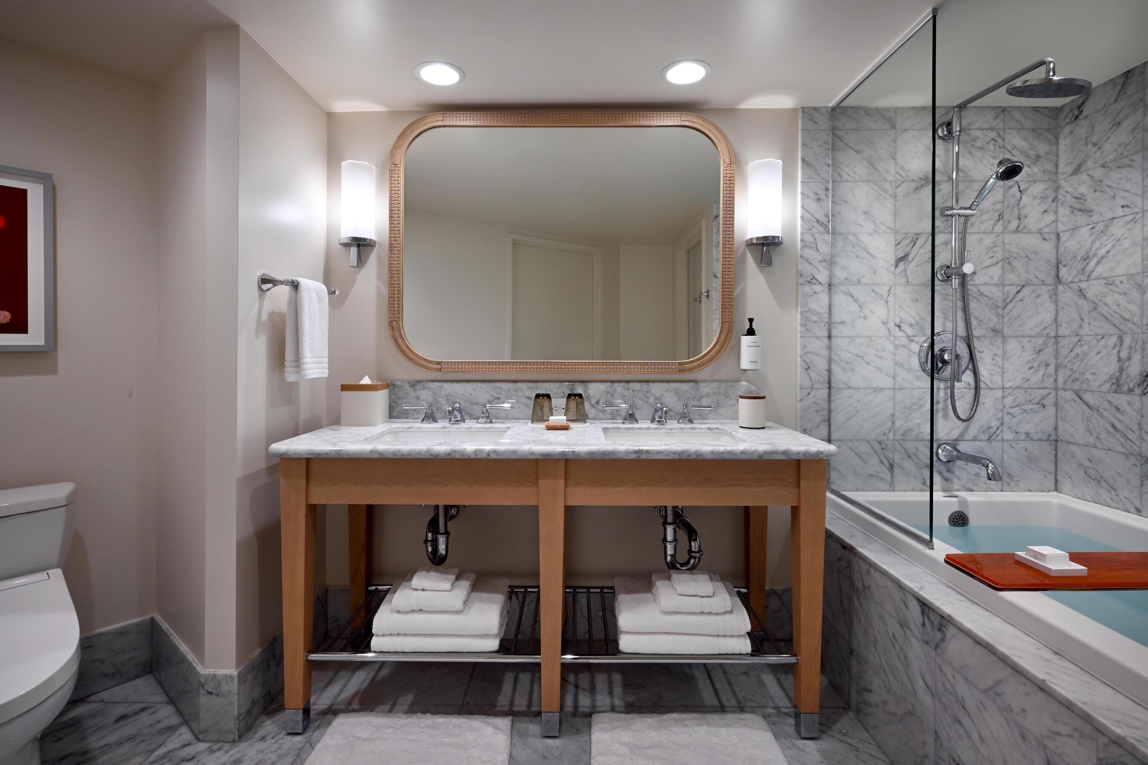 A bathroom with a double sink, a large mirror, a shower, and a bathtub.