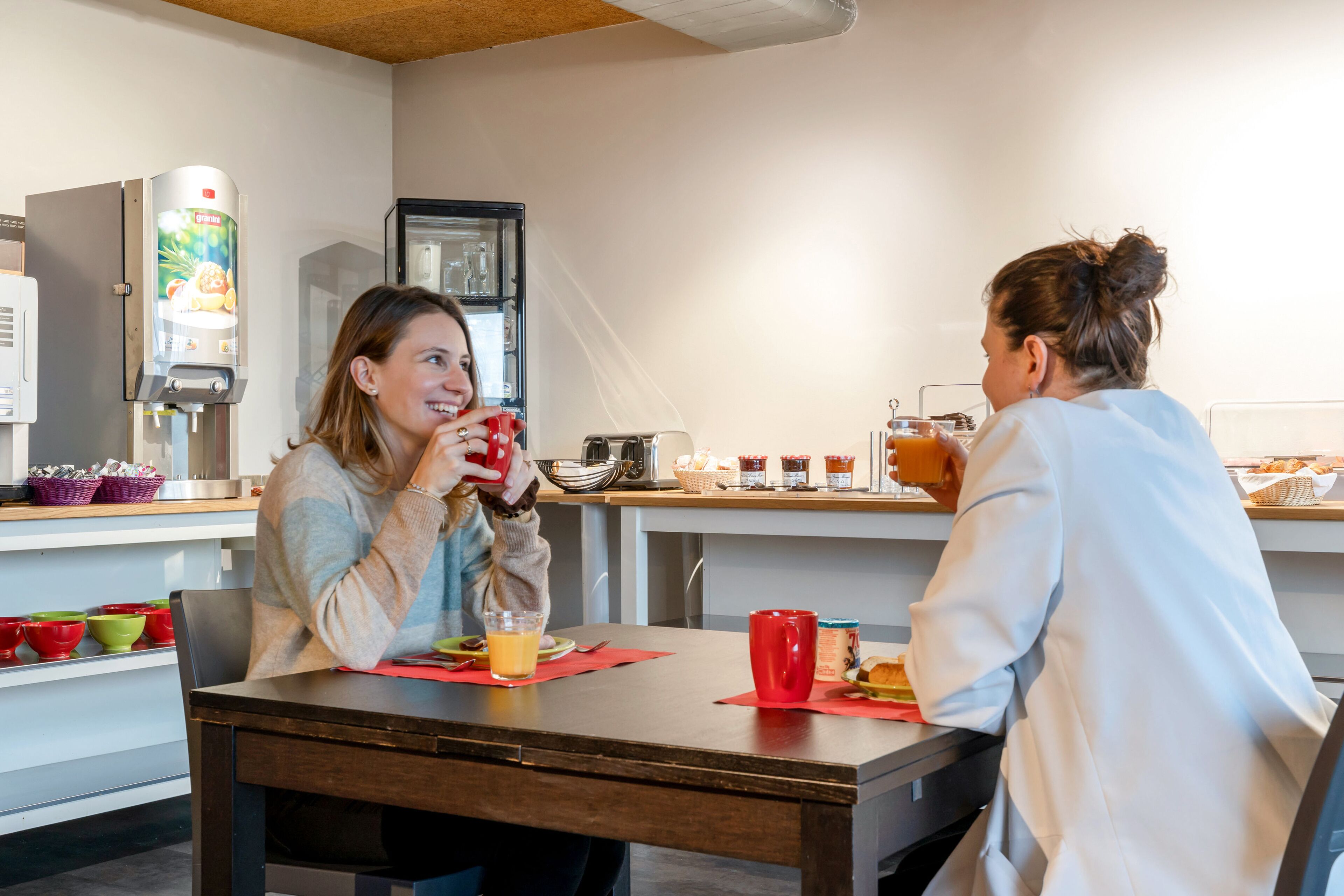 Une table mise pour le petit-déjeuner, avec une machine à café, un réfrigérateur et une sélection de produits pour le petit-déjeuner.