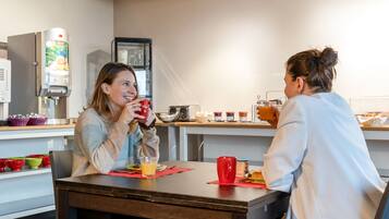 Une table mise pour le petit-déjeuner, avec une machine à café, un réfrigérateur et une sélection de produits pour le petit-déjeuner.