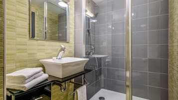 A modern bathroom with a glass-enclosed shower, a white sink, and a mirror above it.