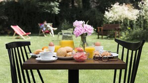 Mesa de desayuno al aire libre con diversos alimentos y bebidas.