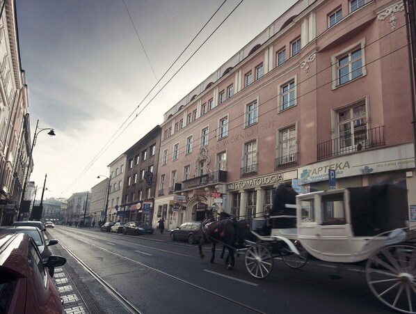 Une rue où l’on peut voir une calèche, des voies de tramway et des immeubles abritant divers commerces.