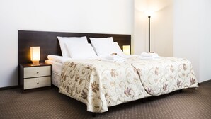 Una cama bien hecha con una colcha estampada con motivos florales, dos almohadas y una mesita de noche con una lámpara.