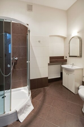 Une salle de bain moderne avec une douche à parois de verre, un lavabo blanc et des toilettes.