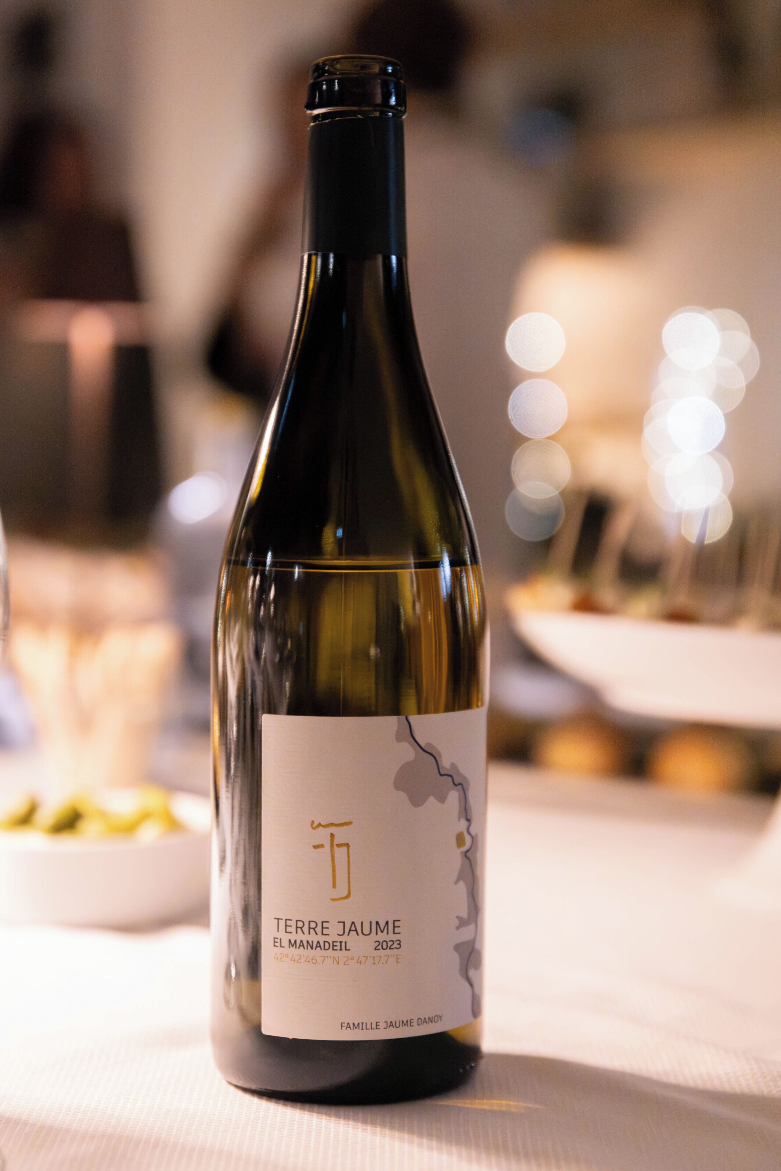 A bottle of Terre Jaume wine on a table with a blurred background.