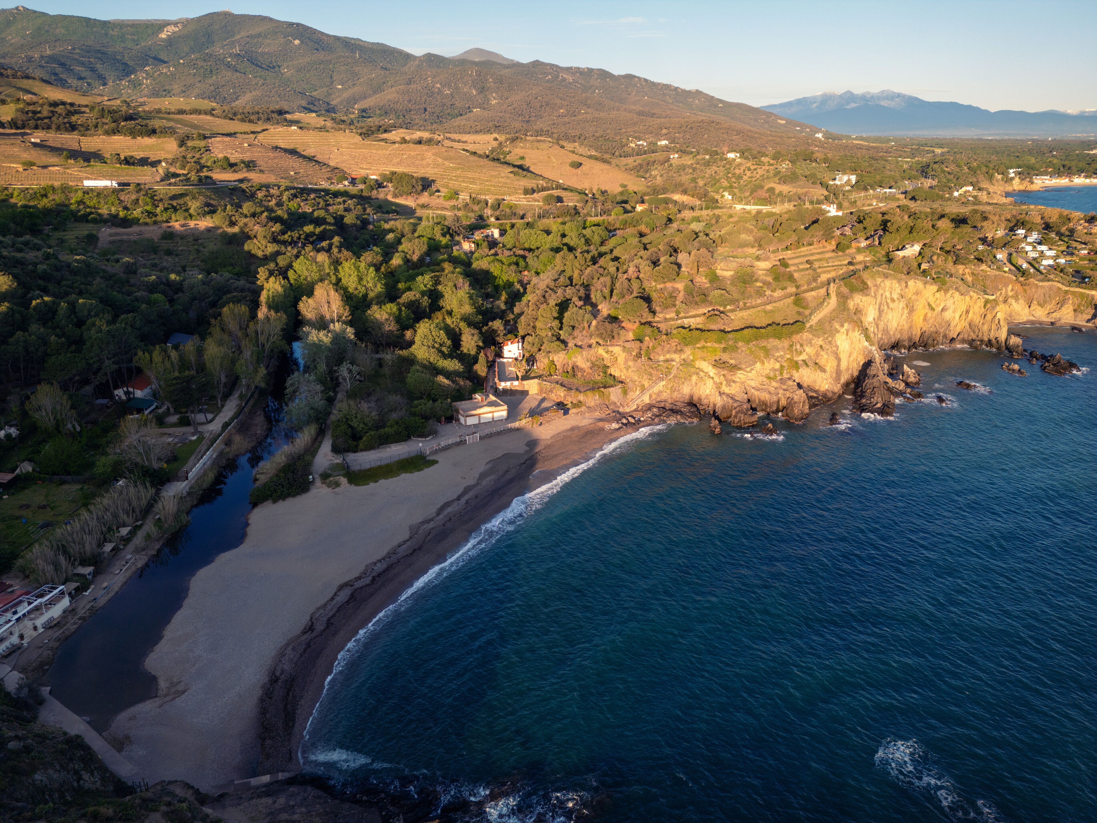 A coastal landscape with a beach, rocky shoreline, and a river.