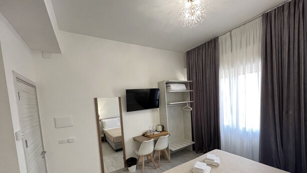 A modern hotel room with a bed, a desk, a chair, a TV, and a wardrobe. - Hotel Ester (Florence)