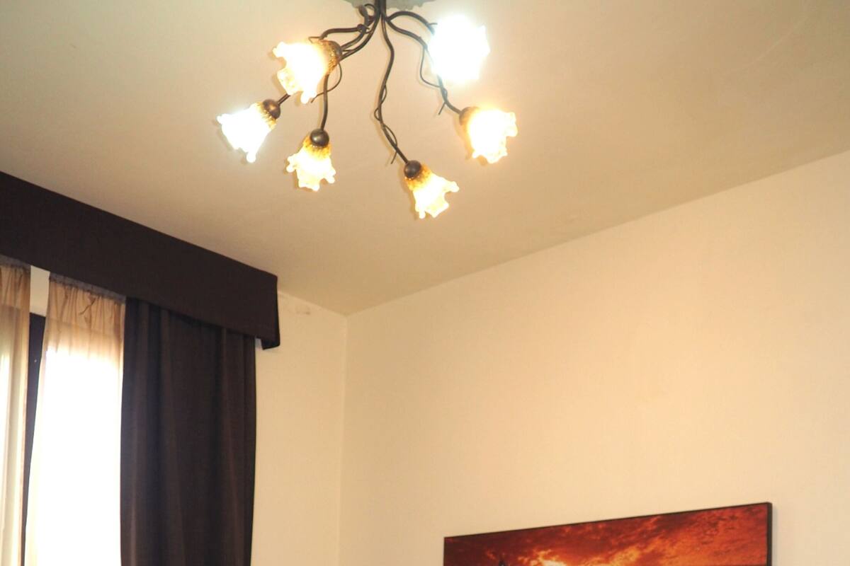 A hotel room with two beds, a chandelier, a painting, and a wardrobe.
