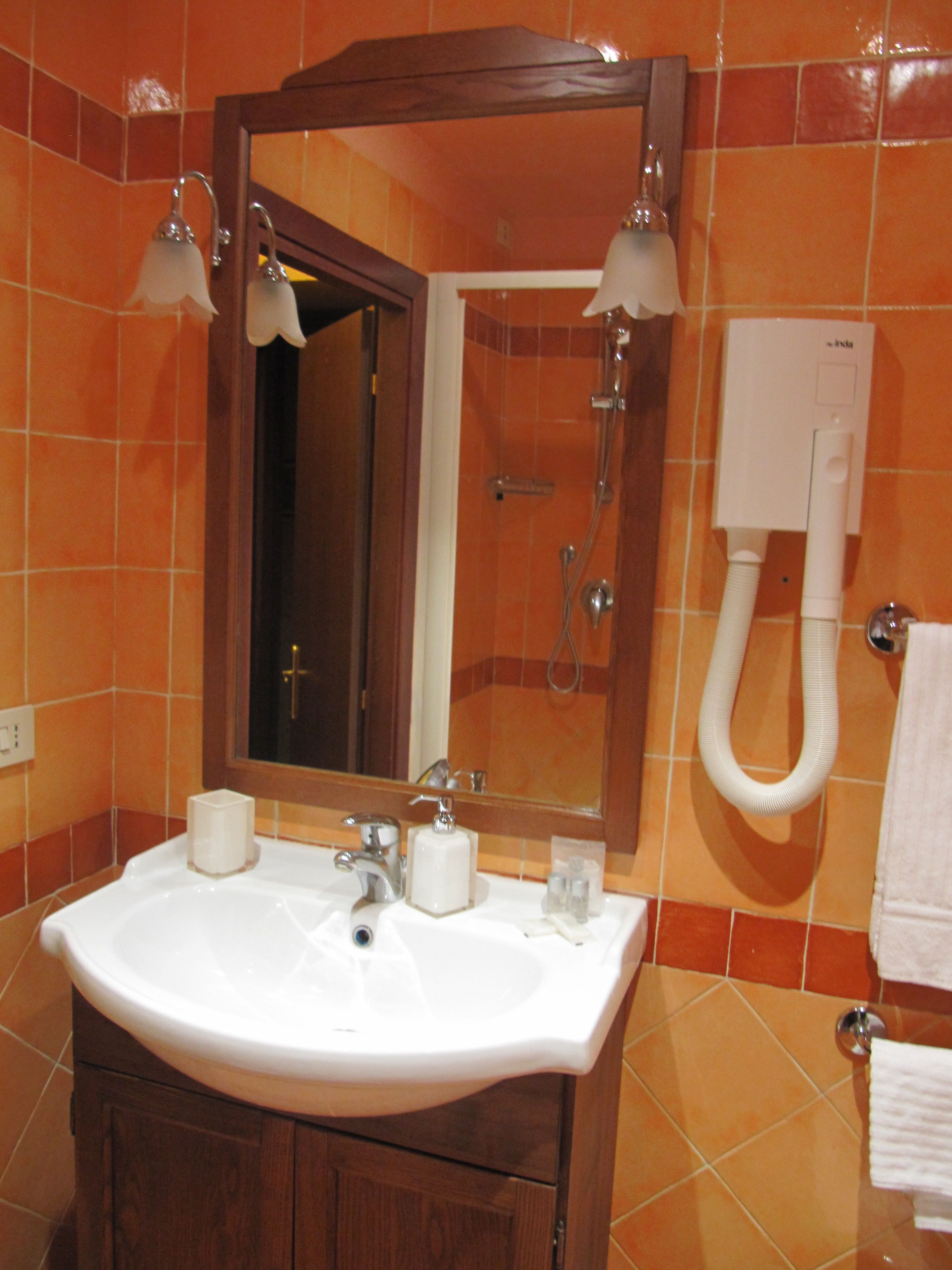 Une salle de bain avec un lavabo blanc, des meubles en bois, un miroir avec éclairage intégré et un porte-serviettes.