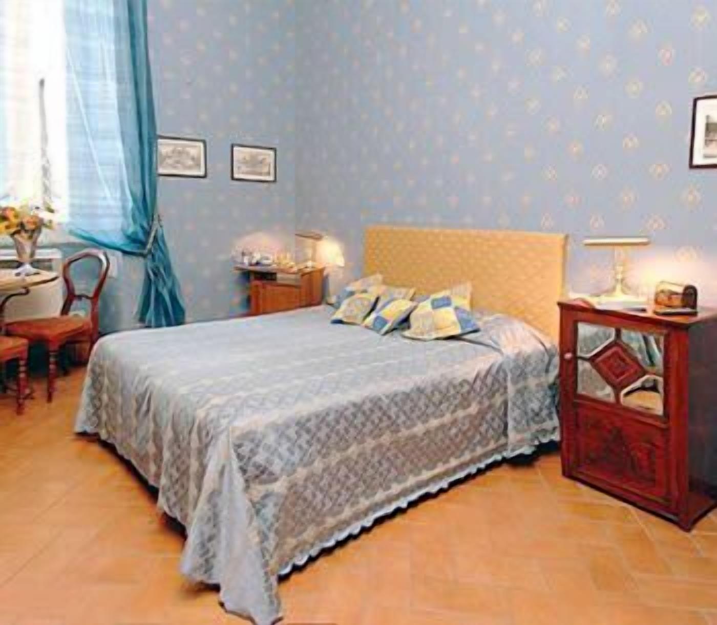 Una camera da letto con un letto, un comodino, una sedia e un tavolino con una lampada.