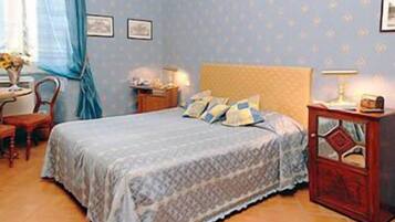 Una camera da letto con un letto, un comodino, una sedia e un tavolino con una lampada.