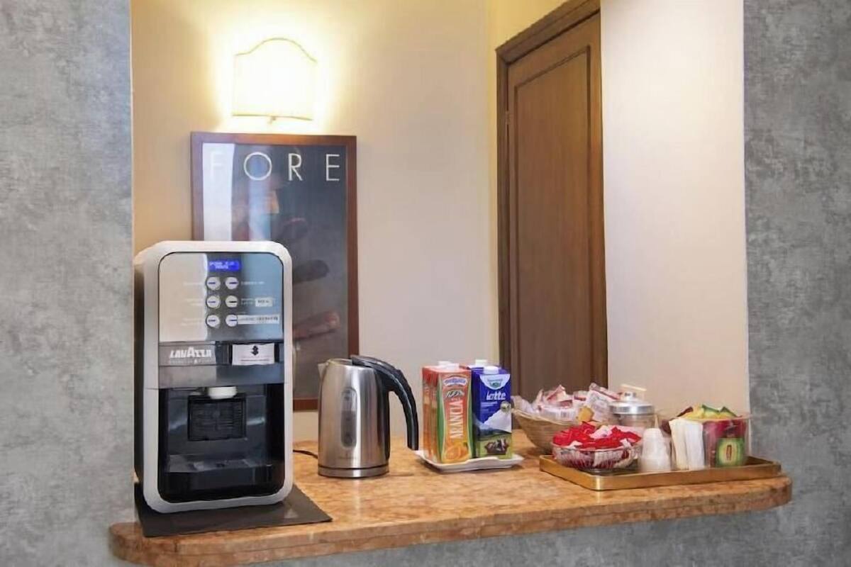Eine Kaffeemaschine, ein Wasserkocher und Frühstücksartikel auf einer Arbeitsfläche.