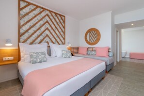 Una habitación de hotel moderna con una cama grande, dos mesitas de noche, un panel decorativo en la pared, un espejo redondo y una pequeña zona de estar.