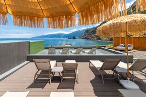 Una piscina techada, una piscina al aire libre, sombrillas