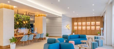 A modern hotel lobby with a reception desk, seating area, and decorative wall panels.