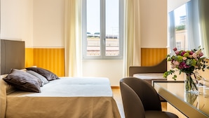 Una habitación de hotel con cama, escritorio, silla, televisor y ventana con vista a la playa.