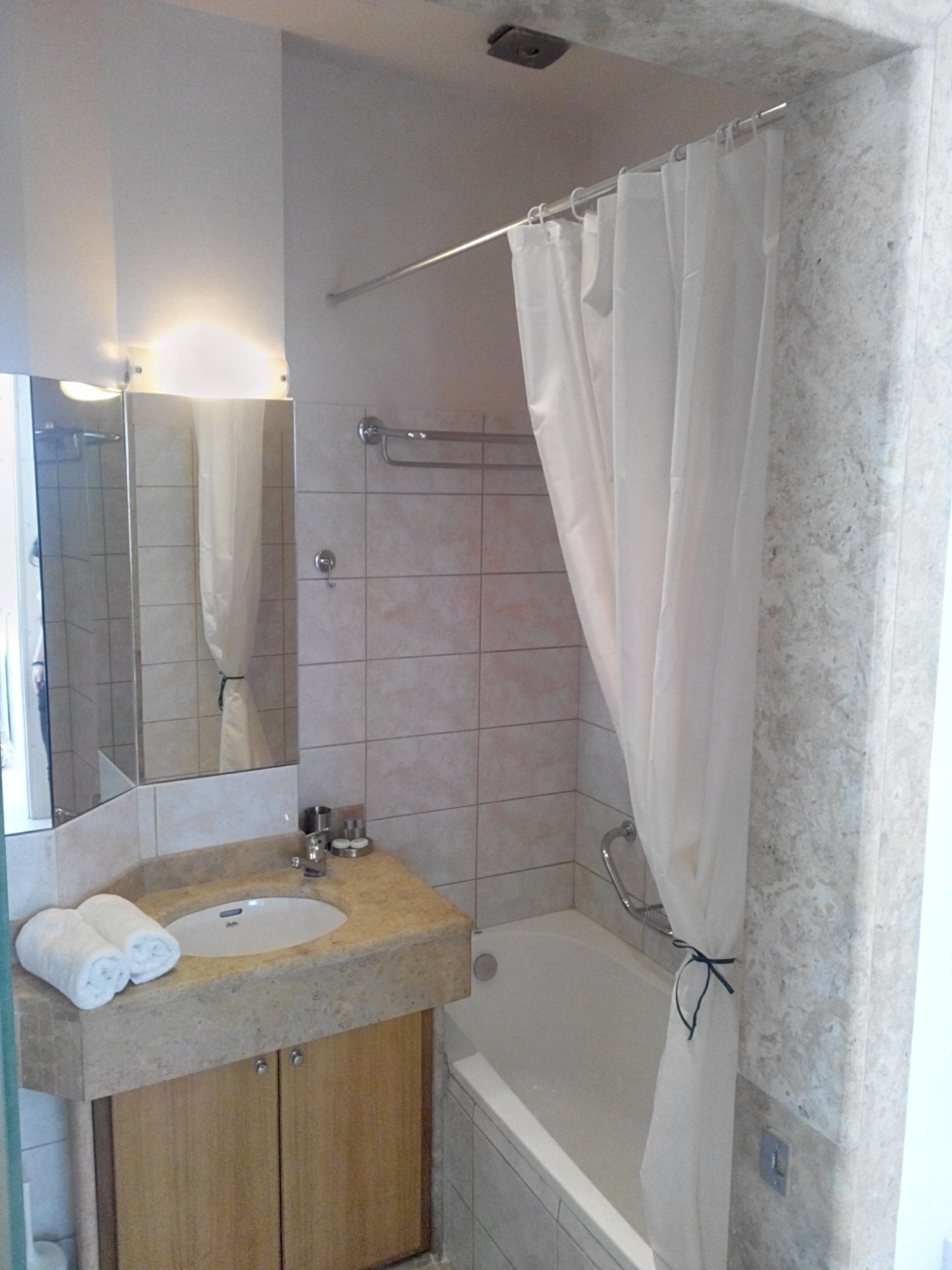 A bathroom with a sink, mirror, and bathtub.