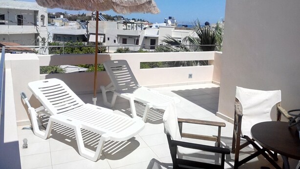A rooftop terrace with white lounge chairs, a table, and a thatched umbrella. - Maria Apartments (Malevizi)