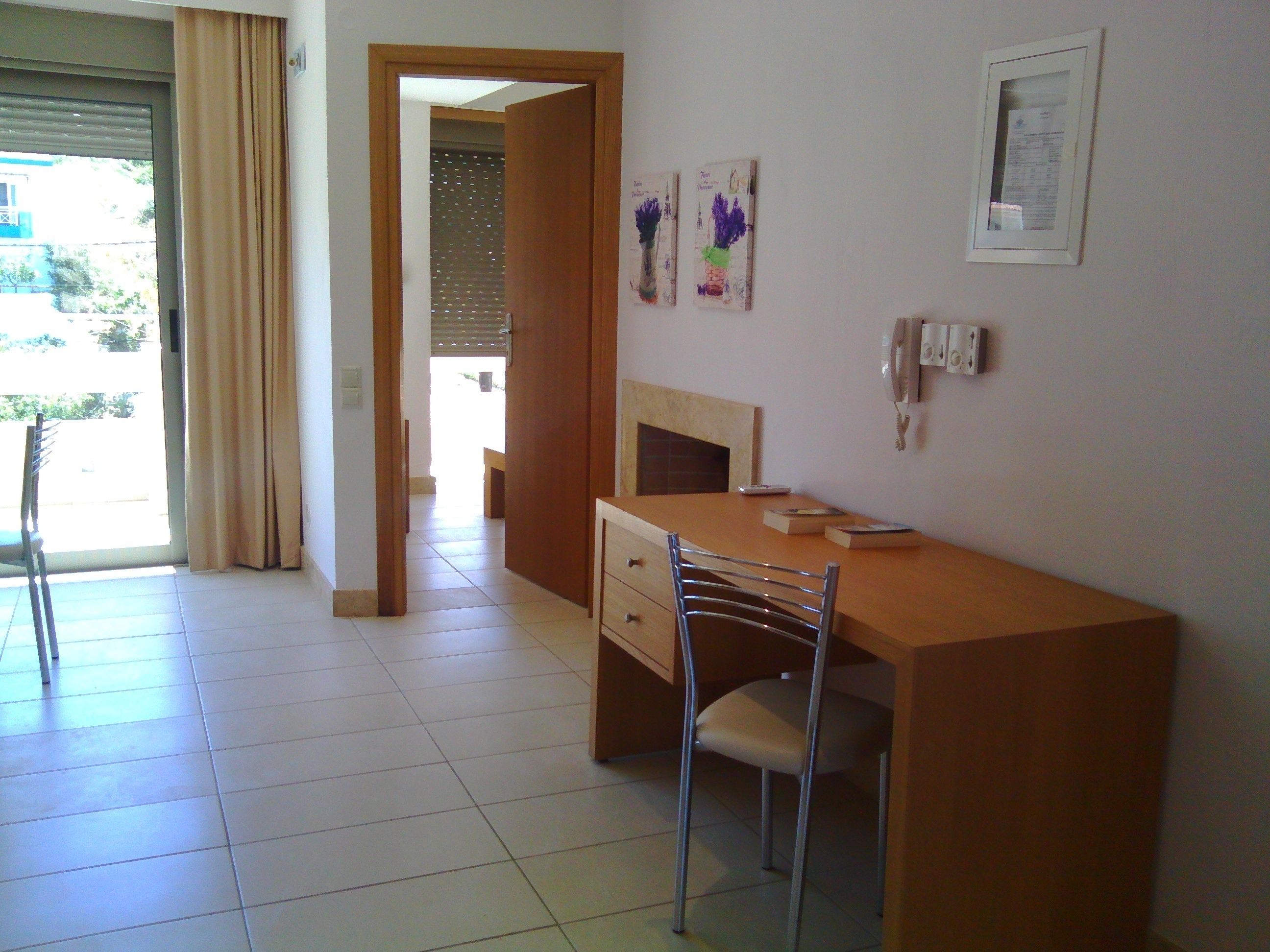 A hotel room with a wooden desk, a chair, a bed, and a bathroom visible through an open door.