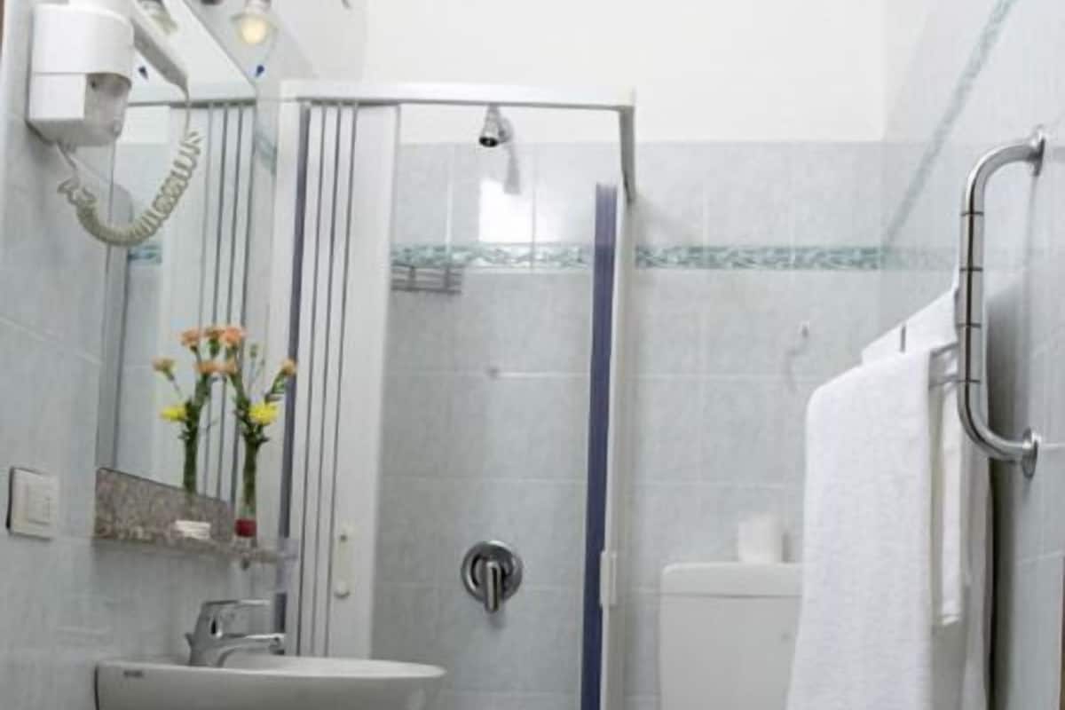 Une petite salle de bain comprenant une douche, des toilettes et un lavabo.