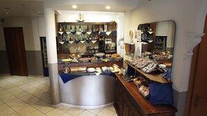 A bar area with a variety of beverages and snacks, a counter with a mirror, and a tiled floor. - Arco Hotel (Milan)