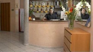 A hotel reception area with a curved counter, a mirror, and a vase of flowers. - Arco Hotel (Milan)