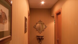 A hallway with wooden paneling, a framed picture on the left, a mirror on the wall, and a door at the end. - Orange Garden Bed & Breakfast (Rome)