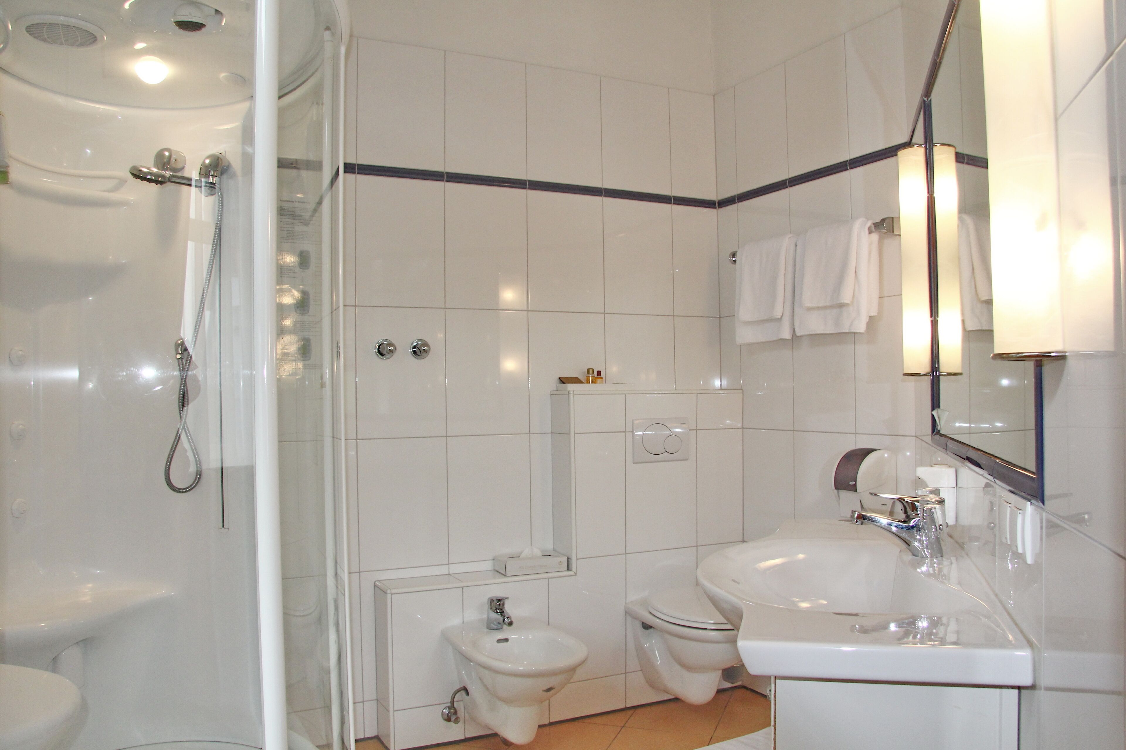 A modern bathroom with a glass-enclosed shower, a sink, a toilet, and a bidet.